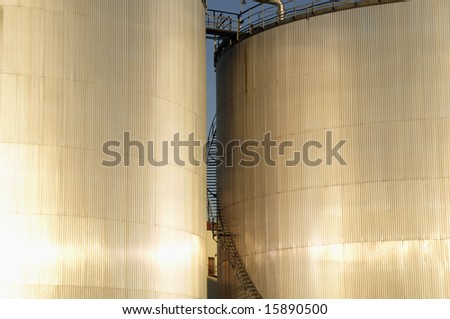 fuel storage tanks in early evening light, sunlight reflecting in metal