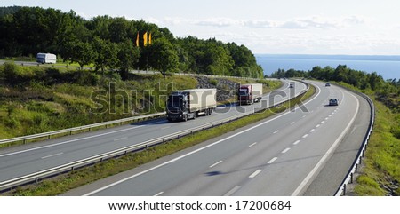 trucks and cars driving on scenic mountain highway, panoramic view.