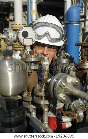 engineer working behind oil and gas pipes inside control-room of refinery