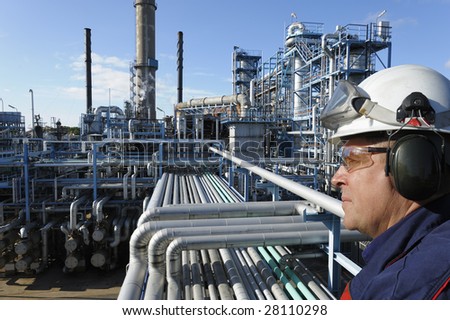 engineer in close-ups standing in front of large oil and gas refinery