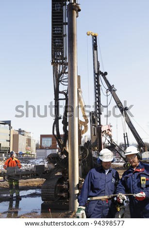 construction workers inside building-site, cranes and excavators in action