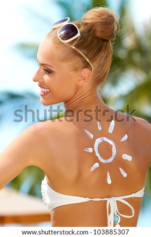 A beautiful blonde woman looking back over her shoulder with a smile at a sun painted on her back