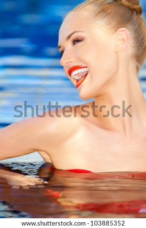 Vivacious laughing woman standing chest high in sparkling blue water