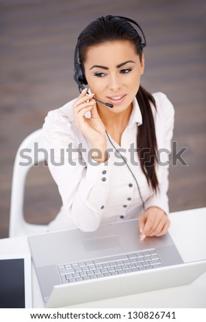 High angle shot of business woman sitting at the desk with headset and laptop