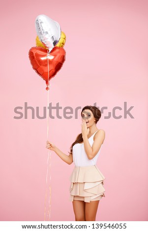 Cute brunette with colorful heart shaped balloons on pink