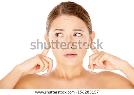 Attractive young woman with bare shoulders blocking her ears with her fingers and looking sideways with a worried expression
