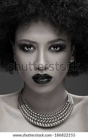 Stunning glamorous African American woman wearing dark makeup looking at the camera with parted lips close up face portrait