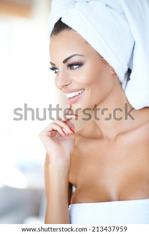 Beautiful young woman enjoying a spa treatment with her hair and body wrapped in fresh white towels smiling with pleasure as she looks to the left of the frame