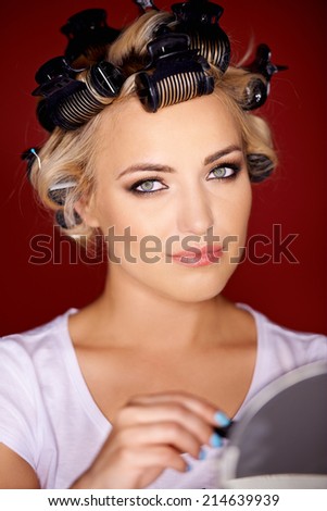 Beautiful young blond woman with her hair in curlers wearing makeup looking at the camera with a serious thoughtful expression