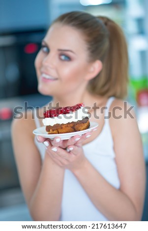 Young woman holding a berry and cream cake in her hands with a smile  focus to the cake