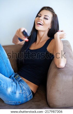Beautiful woman laughing at the television as she enjoys herself watching her favorite program