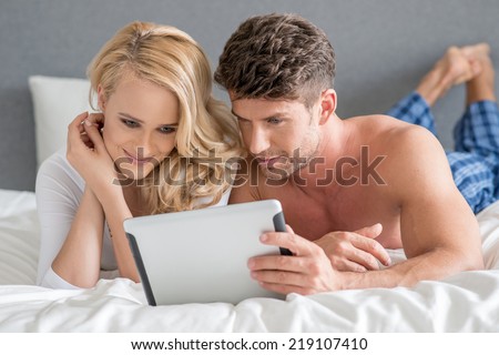 Close up Young Sweet Couple on Bed Watching Something on White Tablet Gadget.