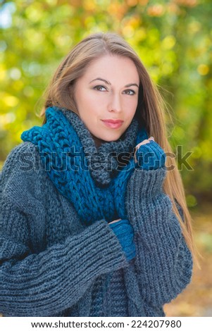 Pretty Young Blond Woman in Thick Gray Knit Jacket During Autumn Season. Looking at Camera. Captured Outdoor.