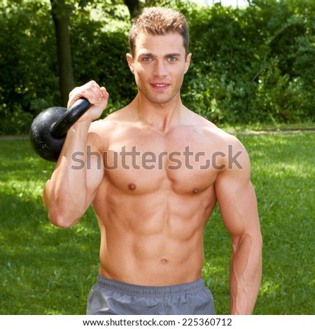 Close up Good Looking Topless Fit Man Carrying Weights Outdoor. Showing Six Packs Abs. Isolated on Nature Background.