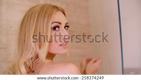 Head and Shoulder Shot of a Bare Pretty Woman with Blond Hair About to Take a Shower at the Bathroom While Looking at the Camera.