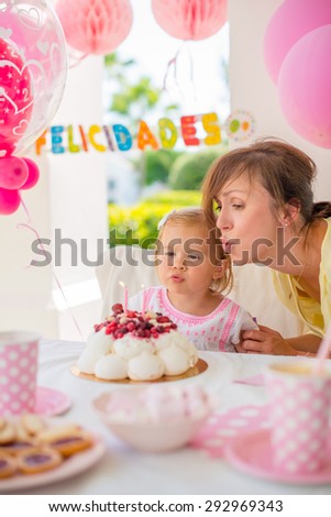 Garden party for the daughter \'s birthday  with mum  Girl makes a wish and blows her candles
