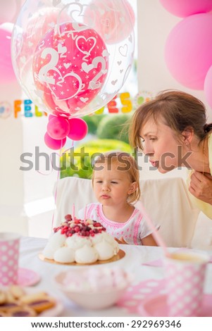 Sweet Cute Girl on Her Birthday Party  She Blowing Candles on Her Cake With a Little Help from Her Mum