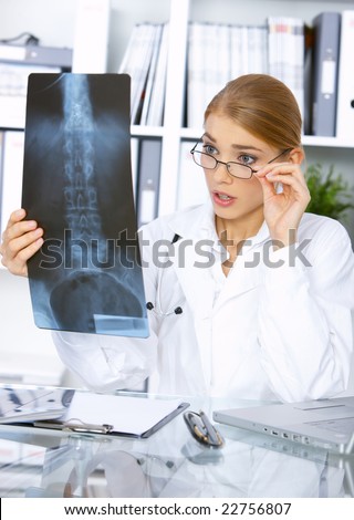 Confused female doctor examining x-ray picture