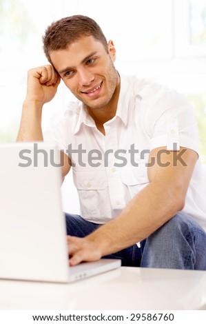 Young man sitting on couch and working on laptop