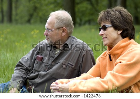 Lovely senior couple enjoying the sun in a green grass field.