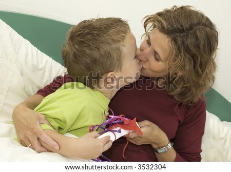 Boy giving his Mothers Day present to his mother. Mother is kissing the boy.