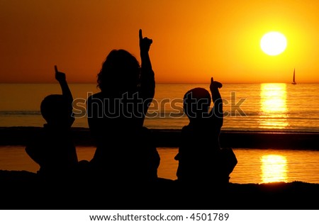 Family looking at a late sunset on the beach, all pointing at the sun.