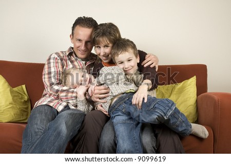 Nice family picture, sitting together on a couch.