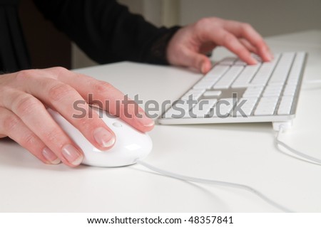 Woman\'s hands working on a keyboard and mouse.