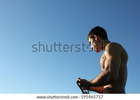 Ripped body builder working out his biceps using a resistance band.