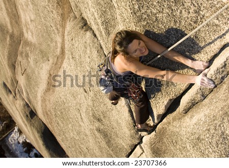 A fit and attractive girl climbs a granite rock in Squamish British Columbia Canada.