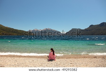 A woman sits at the edge of a clear blue lake in southern Argentina.