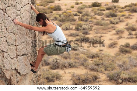 A strong female climber ascends a rock face near Bishop California.