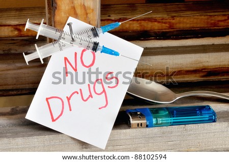 Disposable medical syringe, nailed to a board. Drug abuse concept
