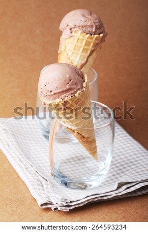 couple of chocolate flavor ice cream cones in a glass on matte texture brown background
