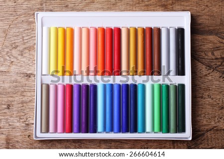 Colorful chalk pastels in box on wooden background - education, arts,creative, back to school