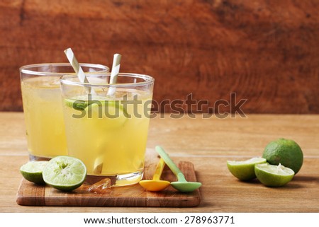 cold gold soft drink from lime and honey with gold straw on wooden board