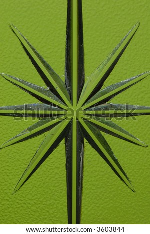 Star carved into a glass pane showing the imperfections of carving and bubbles in the glass with a green background.