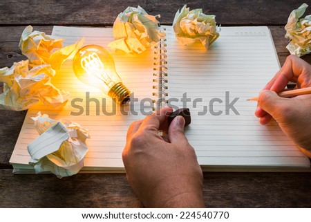Hand write over Note book and light bulb on wood table