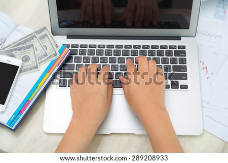 Business woman hand typing on laptop keyboard with Financial charts on the table