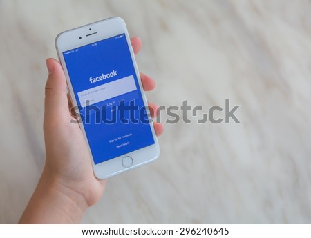 Loei, Thailand - July 12, 2015: Hand holding Iphone with mobile application for Facebook on the screen