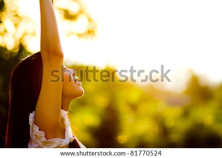 Beautiful young woman enjoys sun beams at summer park