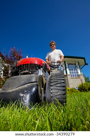 man mowing the front lawn with focus on the front