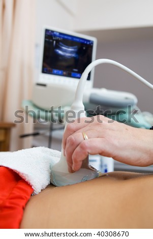 Scanning a female stomach with a ultrasound machine focus on the prob.