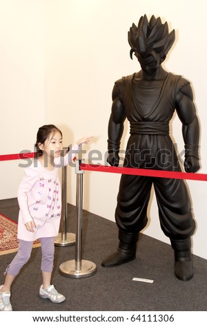 KUALA LUMPUR - OCTOBER 30: A young girl pointing at a life size sculpture of a Dragon Ball character during The Art Expo Malaysia October 30, 2010 in Kuala Lumpur, Malaysia.