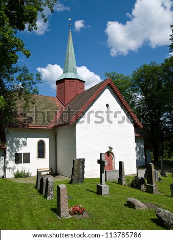 The medieval church at Haslum, a suburb of Oslo in Norway with the church yard in the foreground.