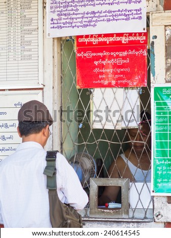 Yangon, Myanmar - November 13, 2014: Man buying a ticket at Pan Hlaing Railway Station in Yangon, Myanmar. Myanmar has a large railway network, but stations as well as trains are old and worn down.