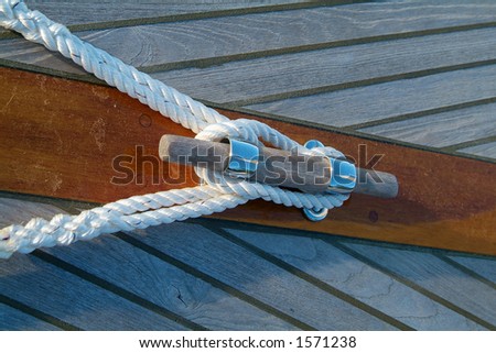Cleat and rope on a wooden sailboat with teak-deck