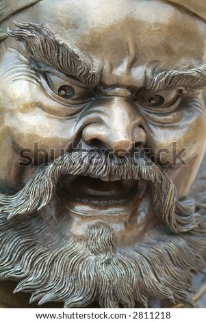 Traditional Chinese bronze sculpture of an angry man with a beard.