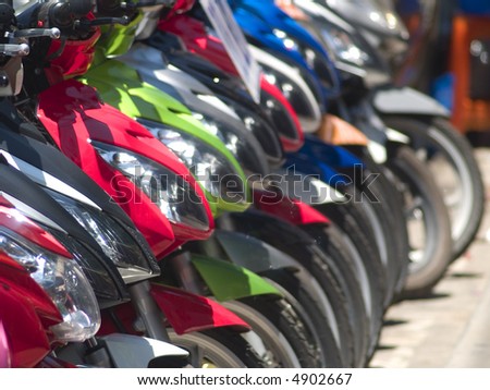 Abstract of front and headlights of light motorbikes parked along the road. Very shallow depth of field.