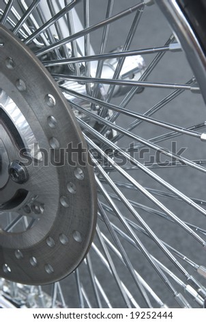 Detail of chrome motorbike wheel with lots of spokes.